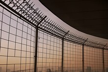 A Wire Fence On High Building With Background Of Sky And Building In The City, Safety And Protect Concept 