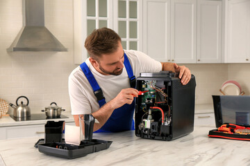 Canvas Print - Repairman with screwdriver fixing coffee machine at table in kitchen