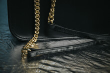 Closeup Of A Black Leather Handbag With A Gold Metal Chain On The Strap