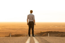 Back View Of A Man Standing In The Middle Of An Empty Highway