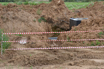 A black septic tanks halfway buried in dirt outside