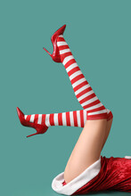 Legs Of Sexy Young Woman In Christmas Stockings On Color Background