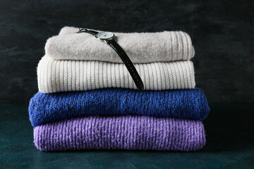 Stack of soft modern sweaters on dark background