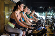 Asian woman in sportive activewear training on bike in spin class at gym