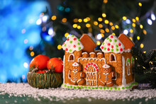 Beautiful Gingerbread House And Tangerines On Table Against Blurred Background