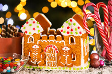 Beautiful Gingerbread House, Snow And Treats On Table Against Blurred Background