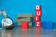 A pocket watch, stack of book and red wooden cube written with QUIZ on a table.