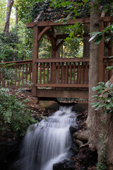 Wall Mural - Vertical shot of a bridge over the small waterfall