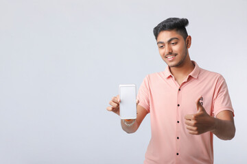 Young indian man showing smartphone screen on white background.