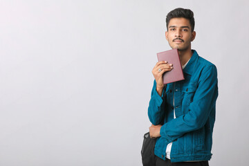 Wall Mural - Young Indian man standing and holding dairy in hand on white background.