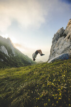 Young Man Jumping In The Air On Top Of A Mountain