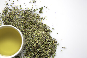 Canvas Print - Top view of a cup of green tea and herbs isolated on a white background