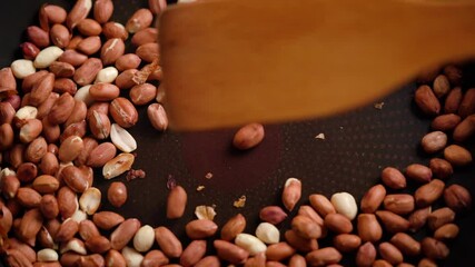 Wall Mural - Production process roasted crunchy nuts. Delicious nuts being roasted in pan. Raw peanuts in shell fried on grill. Skins. 