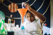 © Maskot - Ambitious girl mixing chemical solution while learning science project at table