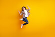 Full size profile side photo of young cheerful girl jump rejoice victory success fists hands isolated over yellow color background