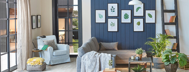 Wall Mural - Modern grey sofa in the blue room with leaf frame, blanket , middle table, lamp, armchair, garden view.