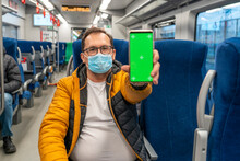 Millennial Man Rides On A Train And Presents A Phone With A Chromakey To The Camera, Shows An Electronic Ticket, Covid Passport, Vaccination Certificate With Qr-code. New Normal Travel Of Tourist