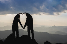 Silhouette Loving Hikers Couple Showing Heart Symbol Hands On Top Mountain Twilight Sunset Background. Valentines Day Concept,