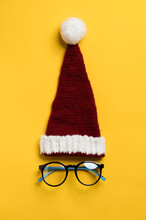 Santa Claus Hat And The Glasses Underneath It Looks Like A Face On A Yellow Background. New Year Sale Of Eye Accessories. 