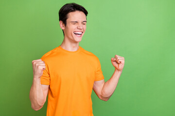 Poster - Photo of happy cheerful happy man good mood raise fists winner celebrate isolated on green color background