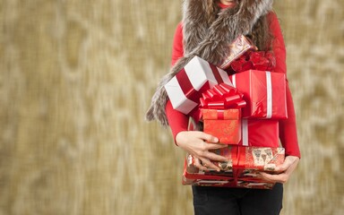 Wall Mural - Young beautiful woman hold paper gift boxes stack against wall. Festive Christmas and New Year holidays celebration concept.