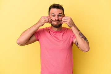 Young caucasian man isolated on yellow background doubting between two options.