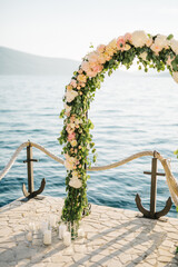 Wall Mural - Wedding arch stands on a cobbled pier by a rope fence with anchors