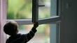 Little boy closing window. Child closes open window
