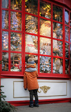 Boy Watching Festive Window Display At Gift Store.  New Year And Christmas Holidays Concept. Child And The Christmas Shop Window. Winter Season