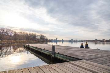 Wall Mural - two people sitting on a dock on the Charles river in Boston