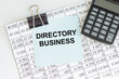 © Volha - DIRECTORY BUSINESS text on sticker on the worksheet with the report next to the calculator on the table. Business concept