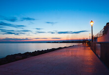 A Walking Path Along The Seaside With Only Shadows Of People, Walking In The Evening
