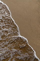 Poster - Vertical top view of foamy waves washing the beachline