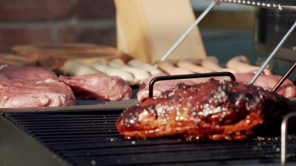 Wall Mural - The cooked meat on a grill with raw meats on background in 4K