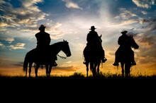 Three Cowboys Silhouetted Against Dawn Sky