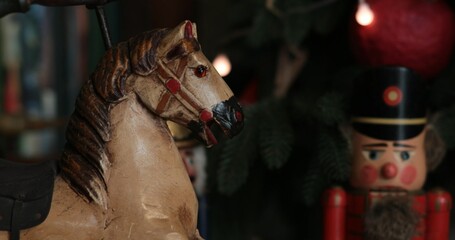  Antique doll horse statuette closeup and out of focus nutcracker nearby. Wooden head of horse vintage figurine made in end of 19 century. Retro Christmas decorations