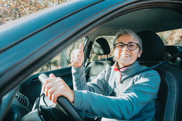 Portrait of a happy smiling senior woman learning to drive a car holding the car key to camera.Safety drive.Learning new hobby,habit and skill for this new year.Old person approving driving license