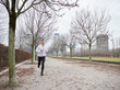 © Stocked House Studio - Adult Man running in the parc in winter with city background