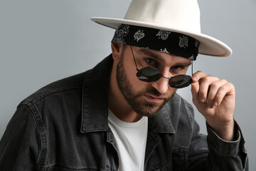 Wall Mural - Fashionable young man in stylish outfit with bandana on grey background