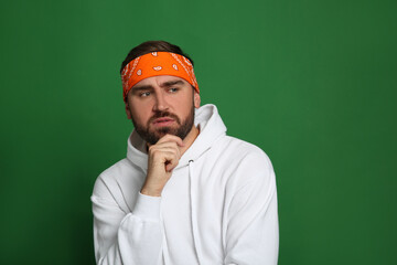 Poster - Fashionable young man in stylish outfit with bandana on green background, space for text