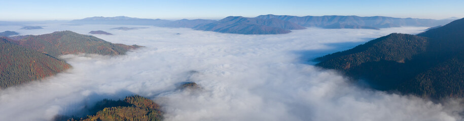 Wall Mural - Autumn mountain landscape panorama. Peaks above the fog. Drone view.