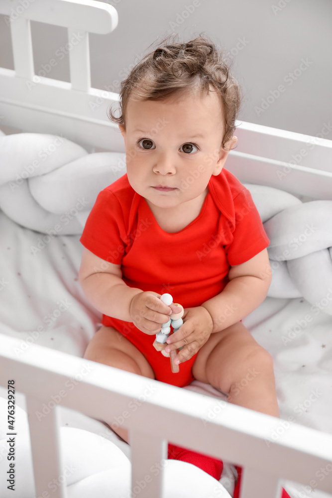 Cute little baby with toy in comfy crib