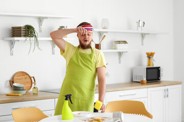 Wall Mural - Young man tired of cleaning dining table in kitchen