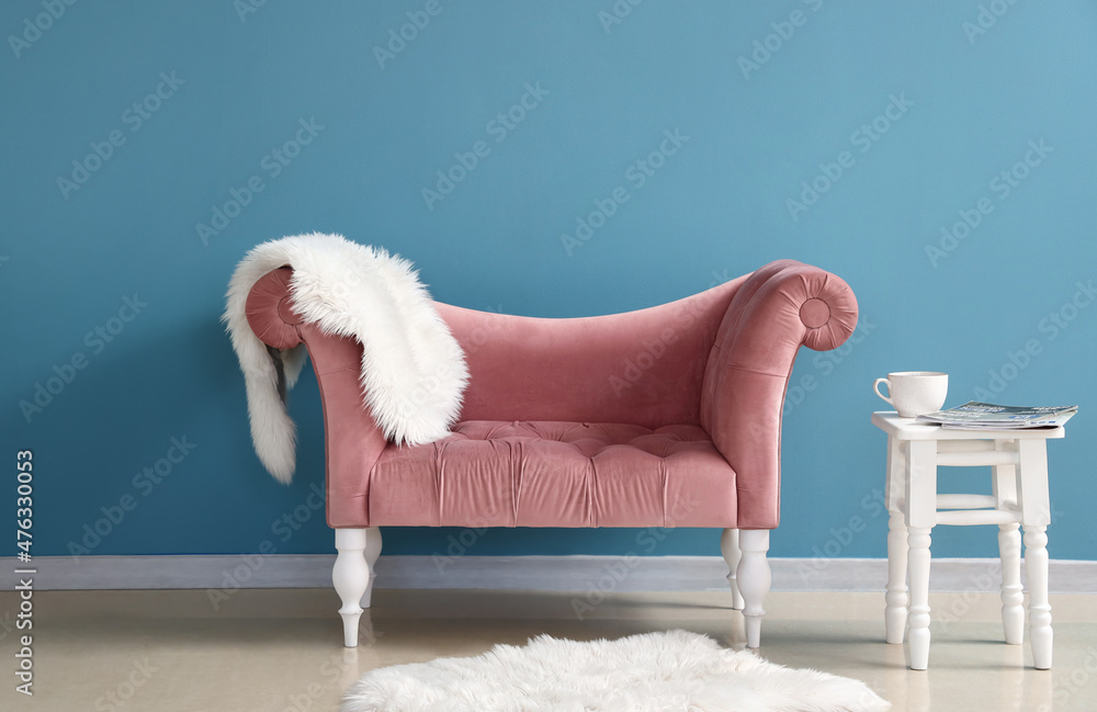 Stylish comfortable armchair with table near blue wall in room