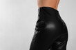 © New Africa - Woman in sexy black leather pants on light background, closeup. Space for text