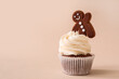 Tasty Christmas cupcake with gingerbread cookie on beige background