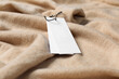 Blank white tags on beige sweater, closeup. Space for text