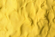 Yellow play dough as background, top view