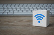 Wi-fi flat icon on white block cube with modern computer keyboard on wooden table, Technology internet communication concept