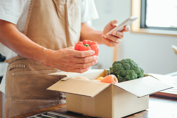 ダンボールに入った野菜と男性（スマホ）
